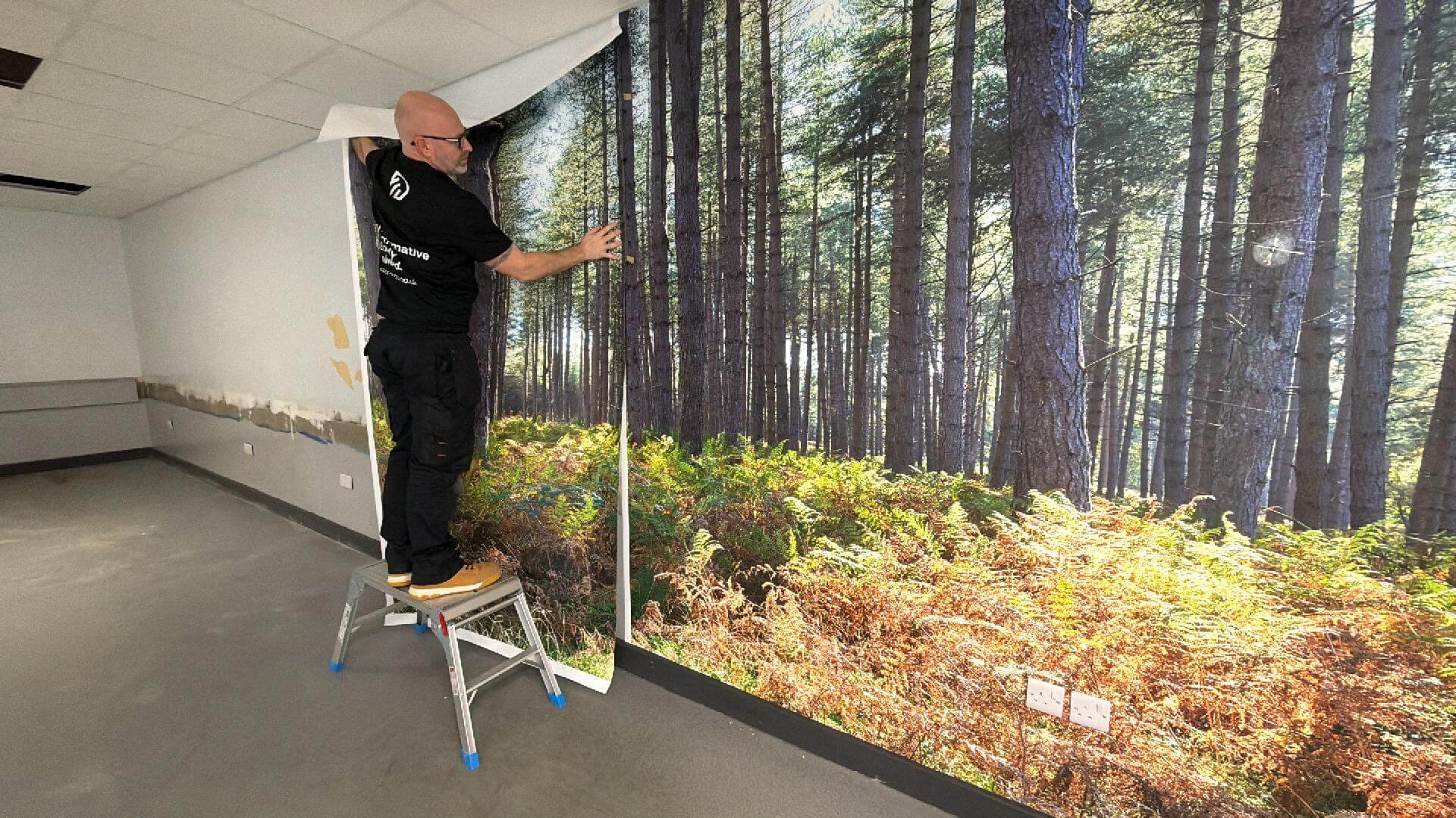 Chris Pitts installing a forest mural