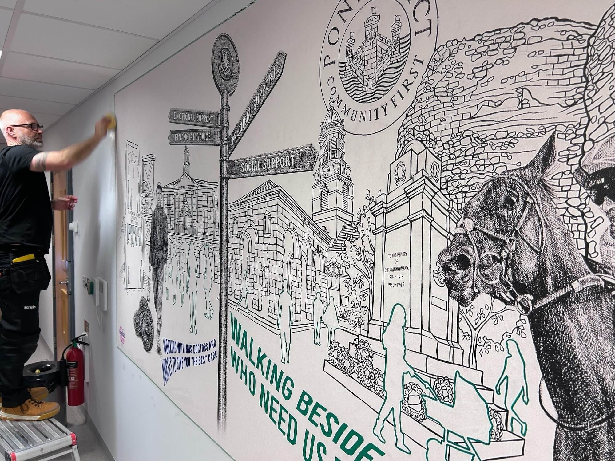 Chris Pitts installing a mural